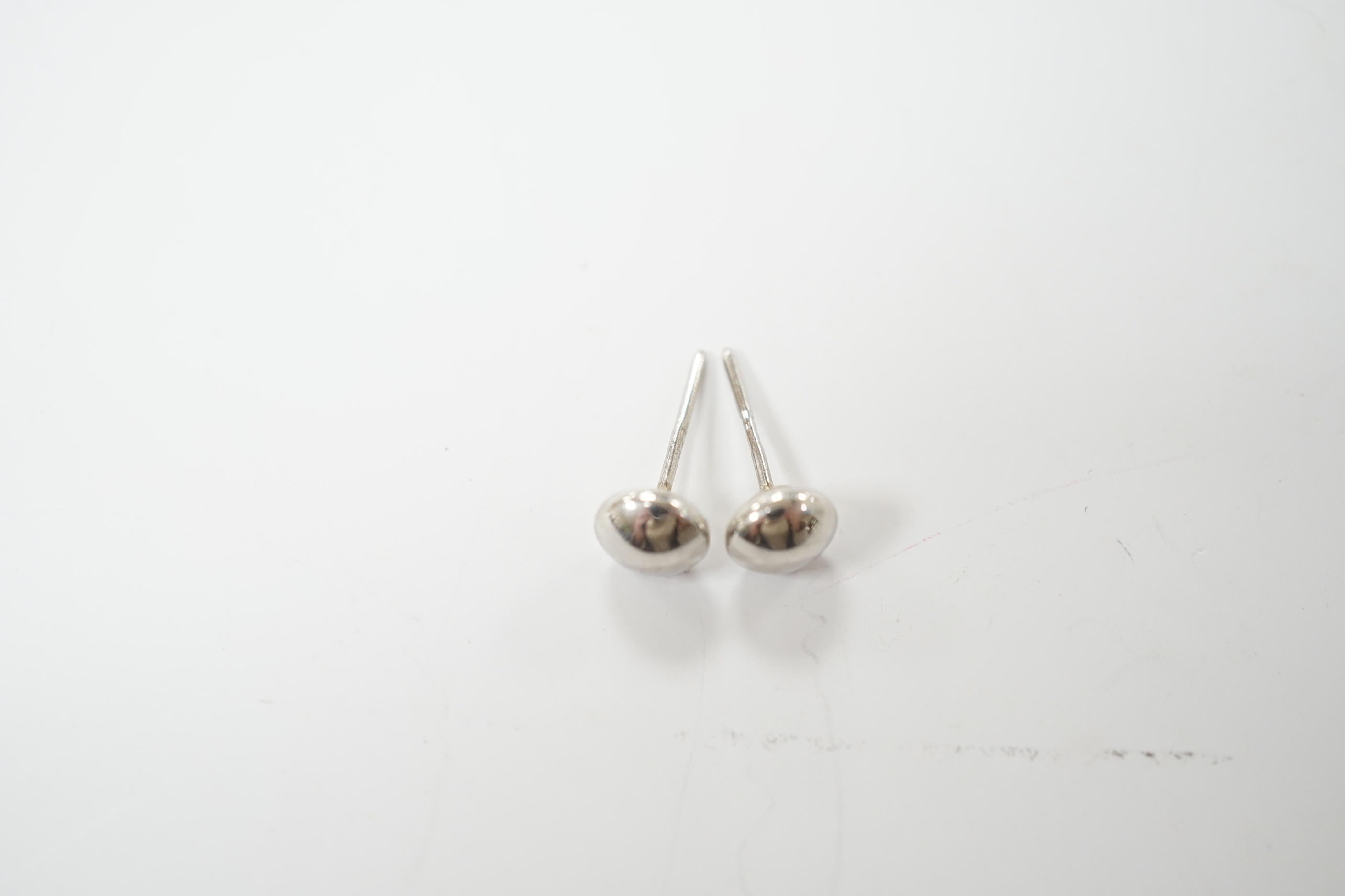 A modern pair of button shaped platinum ear studs, one butterfly missing, 1.1 grams.